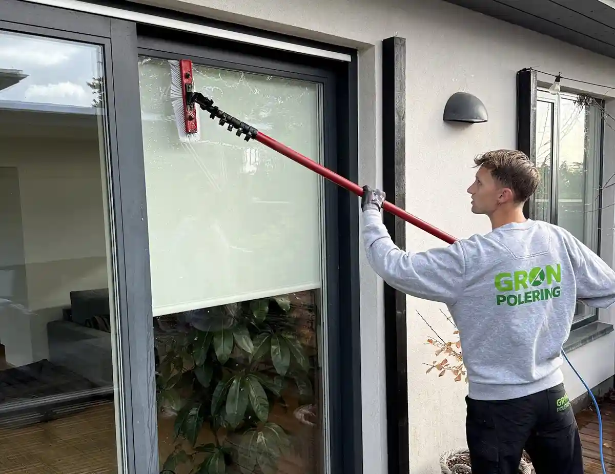 Vinduespudsning med rentvandsstang ved en terrassedør
